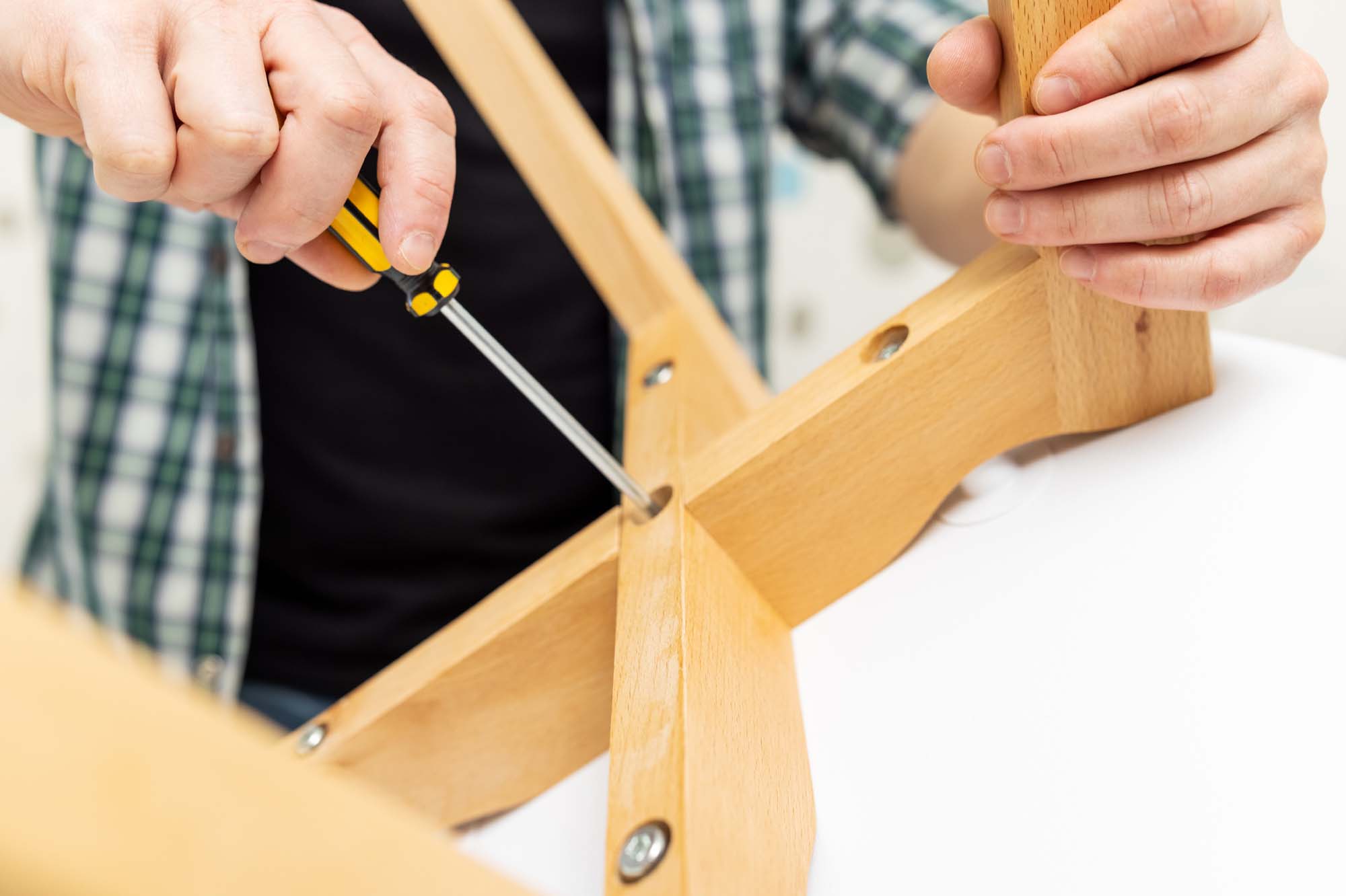 Self-assembly furniture concept. The young man himself assembling chairs. He uses tools for furniture